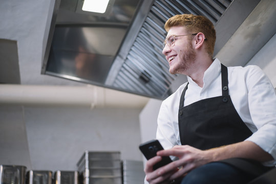 Young cook using smartphone in kitchen