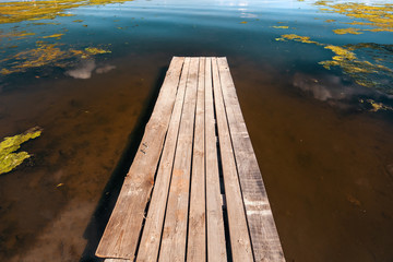 Fototapeta premium Old wooden pier on shore of lake or river with mud