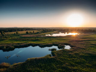 Aerial view of panoramic natural landscape with wetlands, plains with vegetation and lakes at sunset