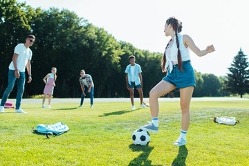 happy teenage multiethnic friends playing with soccer ball in park