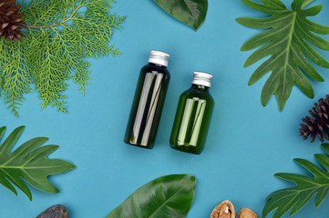 Cosmetic bottle containers on green herbal leaves background, Blank label for branding mock-up,...