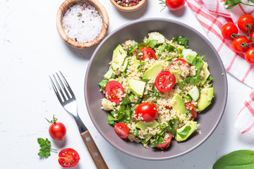 Quinoa salad with spinach, avocado and tomatoes top view.