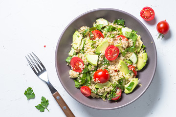 Quinoa salad with spinach, avocado and tomatoes top view.