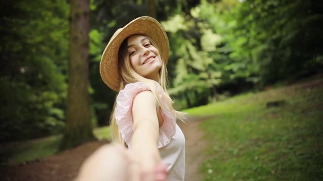 Slow motion woman with hat walking hold man hand look and pose at camera in park couple outside sun smile family behind crossingelegant road together view nature summer beauty enjoy