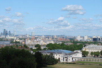 Fototapeta na wymiar Panorama of temples and modern buildings of London from the height of the Greenwich hill against the background of a cloudy blue sky.