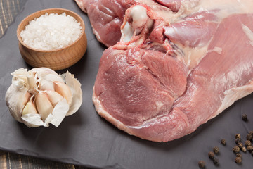 raw turkey meat with bone on black slate, part of thigh, near salt, garlic and spices, picture with details