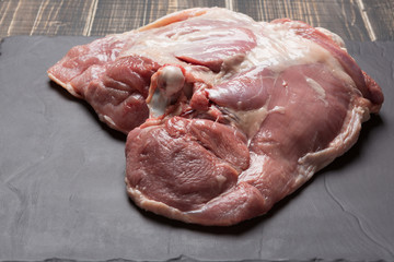 raw turkey meat with bone on black slate, part of hip, close-up shot