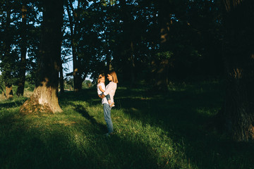 side view of mother hugging cute little daughter while standing in forest