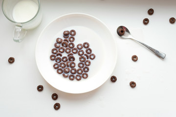 Breakfast with corn rings, milk and cocoa on a white background.