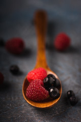 Blueberries and raspberries in an old-fashioned container on a gray concrete background