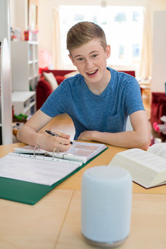 Teenage Boy Doing Homework Asking Digital Assistant Question