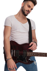 portrait of seductive young rockstar holding his electric guitar