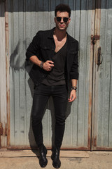 handsome man in black clothes standing outside near garage door
