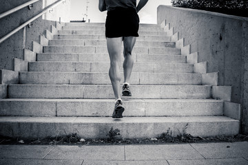 black and white closeup of young man running up the stairs with running clothes - Powered by Adobe