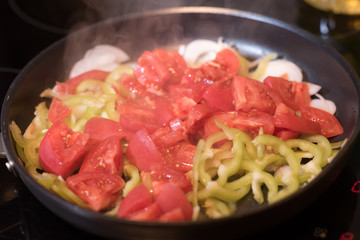 Eggs with tomatoes, green peppers and onions in a frying pan