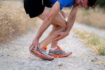 Runner touching painful twisted or broken ankle.