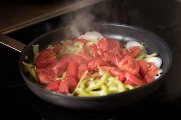 Eggs with tomatoes, green peppers and onions in a frying pan