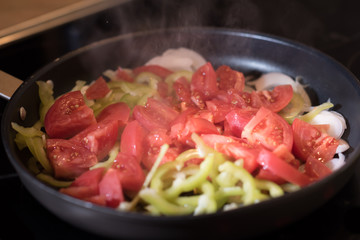 Eggs with tomatoes, green peppers and onions in a frying pan
