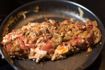 Eggs with tomatoes, green peppers and onions in a frying pan