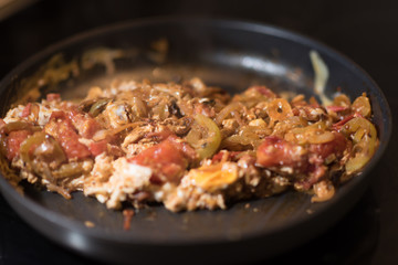 Eggs with tomatoes, green peppers and onions in a frying pan