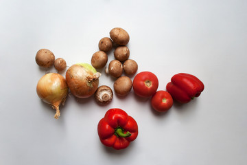 Red sweet peppers, tomatoes, onions and brown champignons isolated on white background from a high angle view