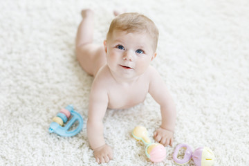 Cute baby girl playing with colorful pastel vintage rattle toy