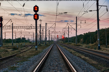 Naklejka premium kolejowe światła i infrastruktura podczas pięknego zachodu słońca, kolorowe niebo, transport i koncepcja przemysłowa