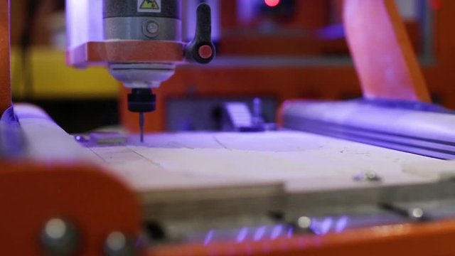 CNC milling machine while carving a wooden table. cutter controlled by a computer while he is carving wood. Instrumentation for FabLab and Makerspace suitable for digital manufacturing.