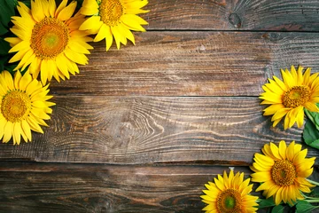Fotobehang Mooie zonnebloemen op een houten tafel. Uitzicht van boven. Achtergrond met kopie ruimte. © Anna