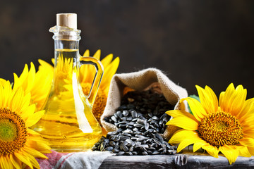 Closeup photo of sunflowers and sunflower oil with seeds on on a wooden table. Bio and organic...