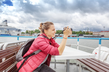 Young beautiful happy girl traveler with a camera in her hands examines the places of Helsinki, the...