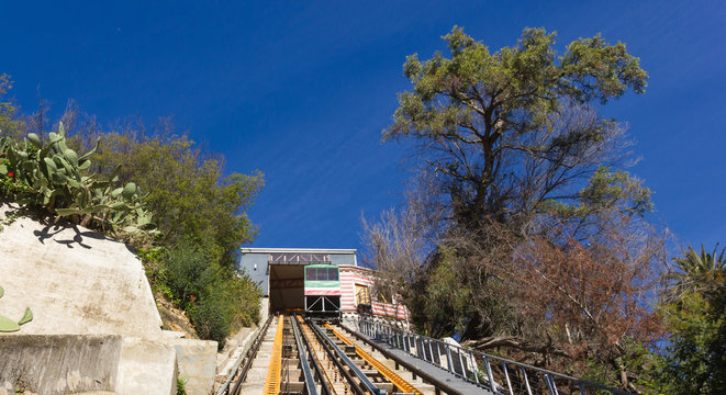 Tracks of street elevator surrounded by trees and cactus on sunny day in Valparaiso, Chile. Old traditional transportation