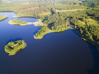 Aerial view of small uninhabited island (Wyspa Pozeracza Serc) on lake with sky reflected in calm water, Krzywa Kuta Lake, Mazury, Poland