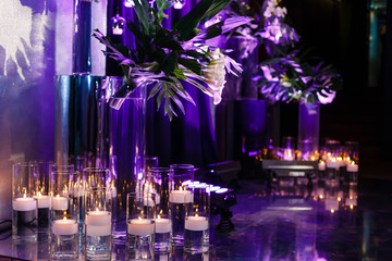 Burning candles in glass flasks stand on the floor of celebraiotn hall. Background. Copy space.