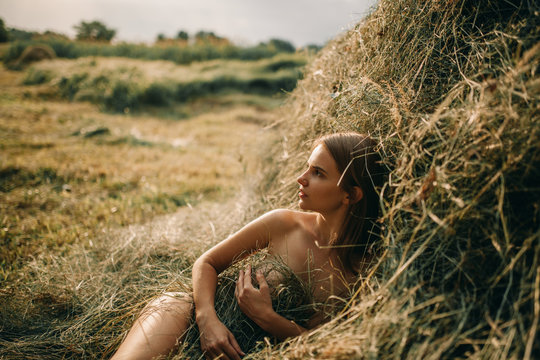 Young Naked Woman Lies Near Haystack.