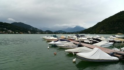 Time Lapse of lake Lugano-Ceresio with small dock with boats in Lavena Ponte Tresa, province of Varese, Italy