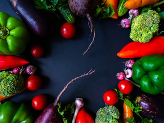 Fresh vegetables on a black background. Tomatoes, peppers, garlic, eggplant, beets, broccoli, carrots, cucumber.