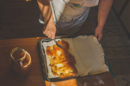 Apple jam next to the baking sheet of rolled dough