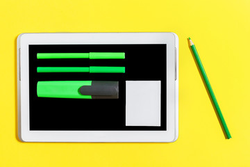 green bright felt pen, marker and paper stickers on the screen of the tablet pc. green pencil lying...
