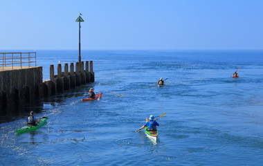 Kayaker passing wooden groyne on the sea near town of Seaton in East Devon