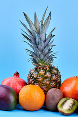 Composition of tropical and mediterranean fruits. Assortment of delicious exotic fruits on blue background, front view.