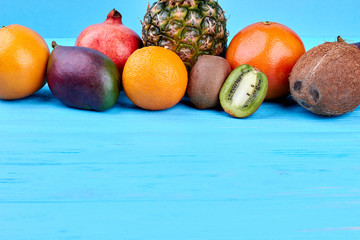 Assortment of exotic fruits and copy space. Variety of tasty tropical fruits including orange, mango, pomegranante, pineapple, kiwi fruits, grapefruit and coconut.