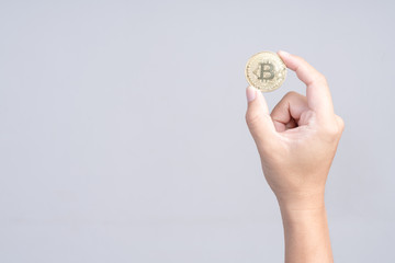 Hand holding golden bitcoin on white background