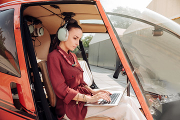 Naklejka premium Luxury trip. Successful beautiful woman wearing headphones and using laptop