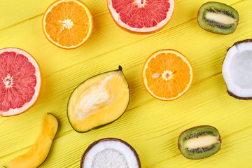 Yellow wooden background with tropical fruits. Exotic fruits color background. Summer healthy ingredients.