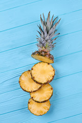 Ripe pineapple sliced in pieces, top view. Flat lay composition with fresh sliced pineapple on blue wooden background.