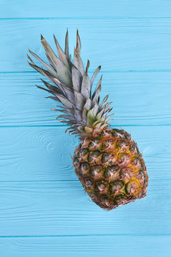 Healthy pineapple on color wooden surface. Ripe ananas on blue wooden background, top view.
