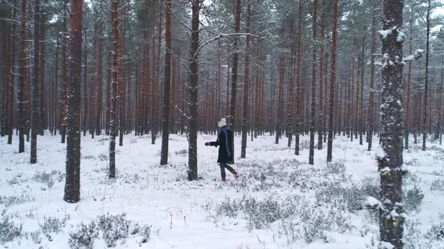Woman walking in snowy forest in winter dolly shot