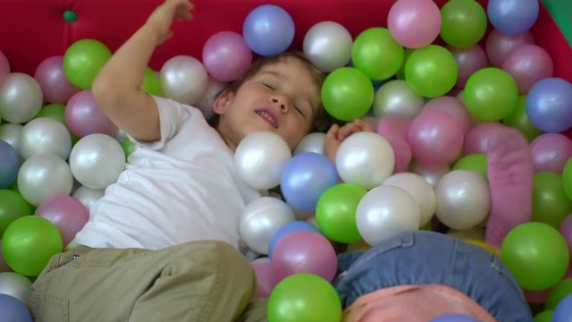 Happy preschool children playing in multi coloured ball pool. Nursery school