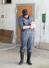 junger Bauer hält liebes Ferkel in der Hand